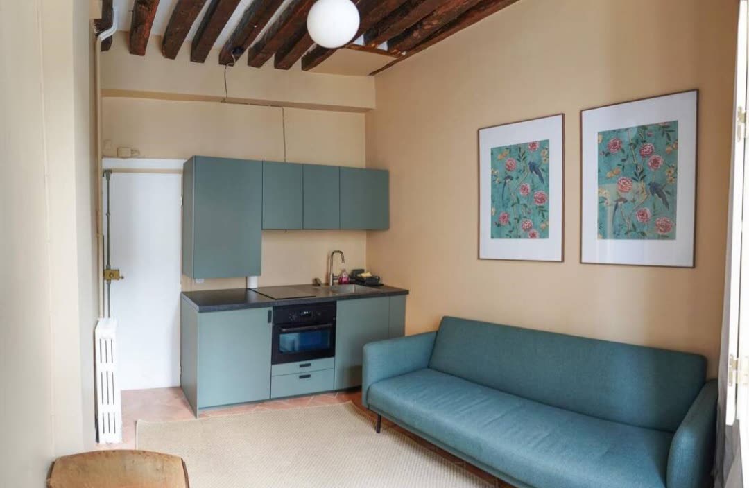 Living room of Studio Le Marais with open-plan kitchen, exposed wooden beams and blue sofa