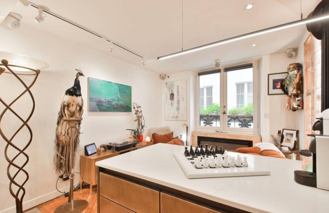 Lounge area with fireplace, artwork and French window in the Marché Saint-Honoré duplex