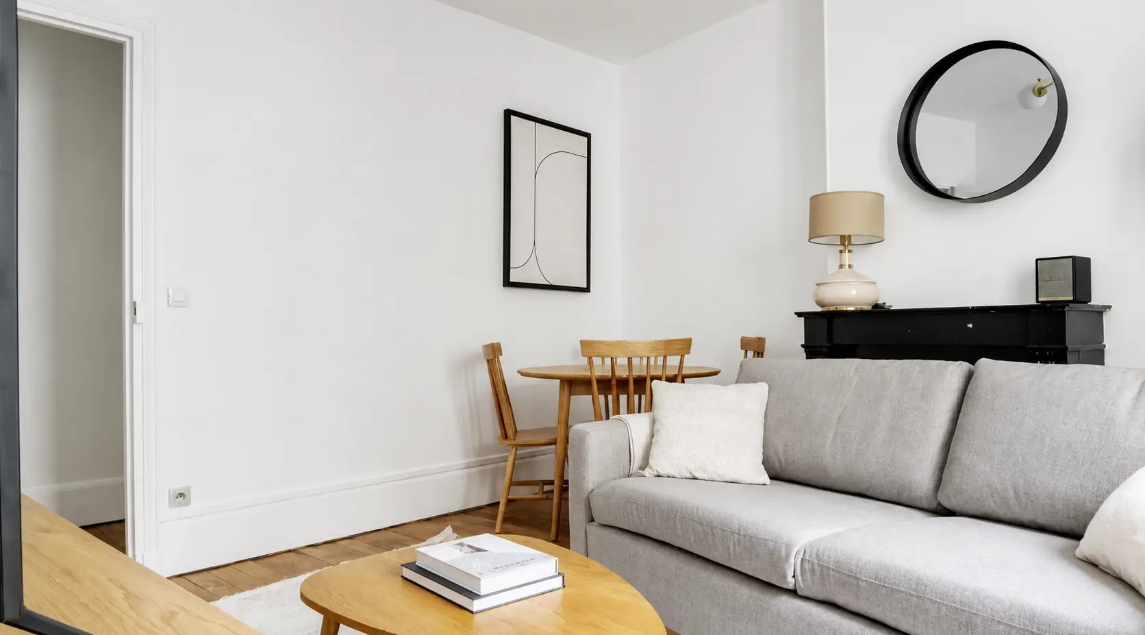 Living and dining area with round wooden table and period fireplace — Le Marais · Paris 4th, Paris, France