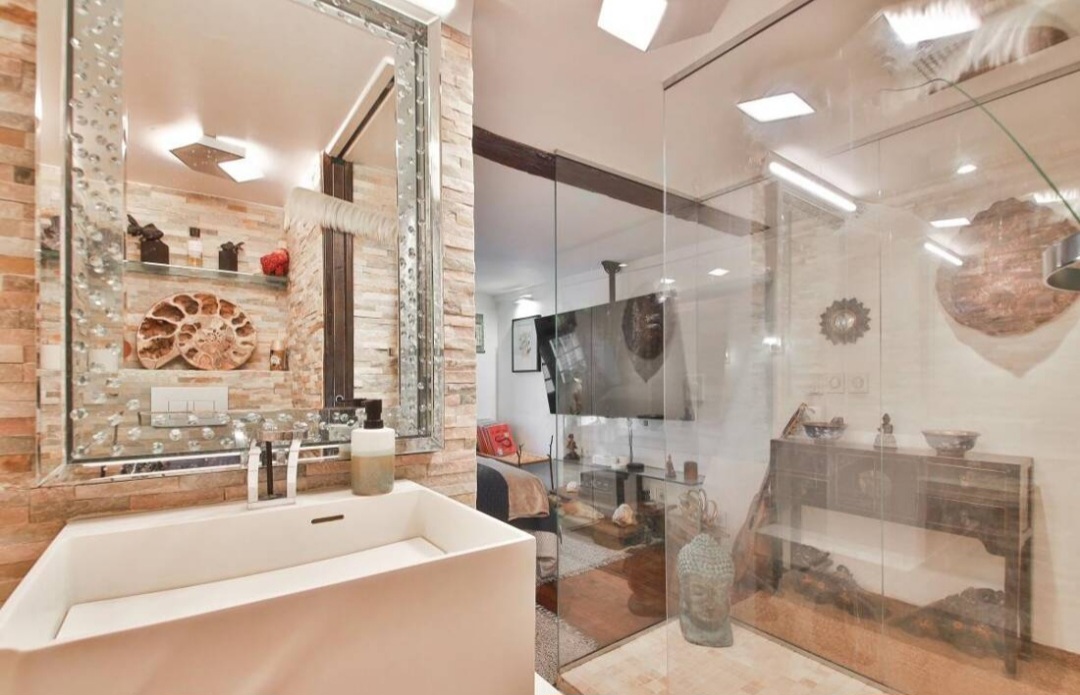 Bathroom with stone-clad walls, designer basin and mirrored vanity