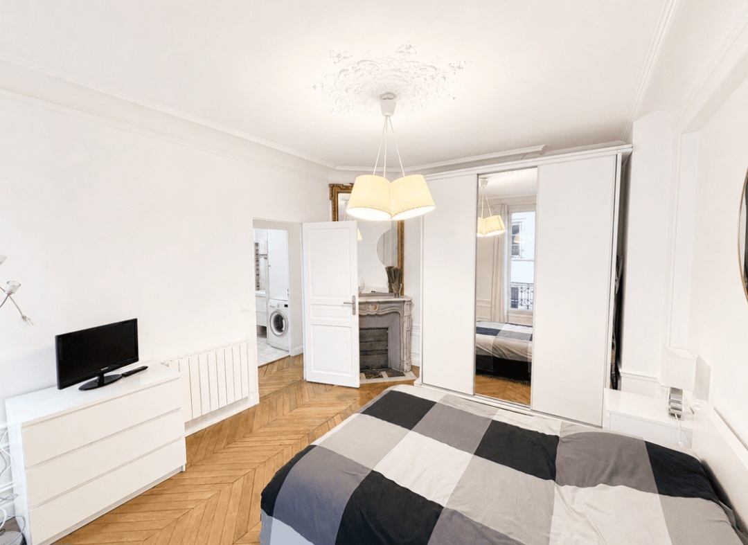 First bedroom with fitted wardrobes, chest of drawers and television — Le Marais · Paris 4e