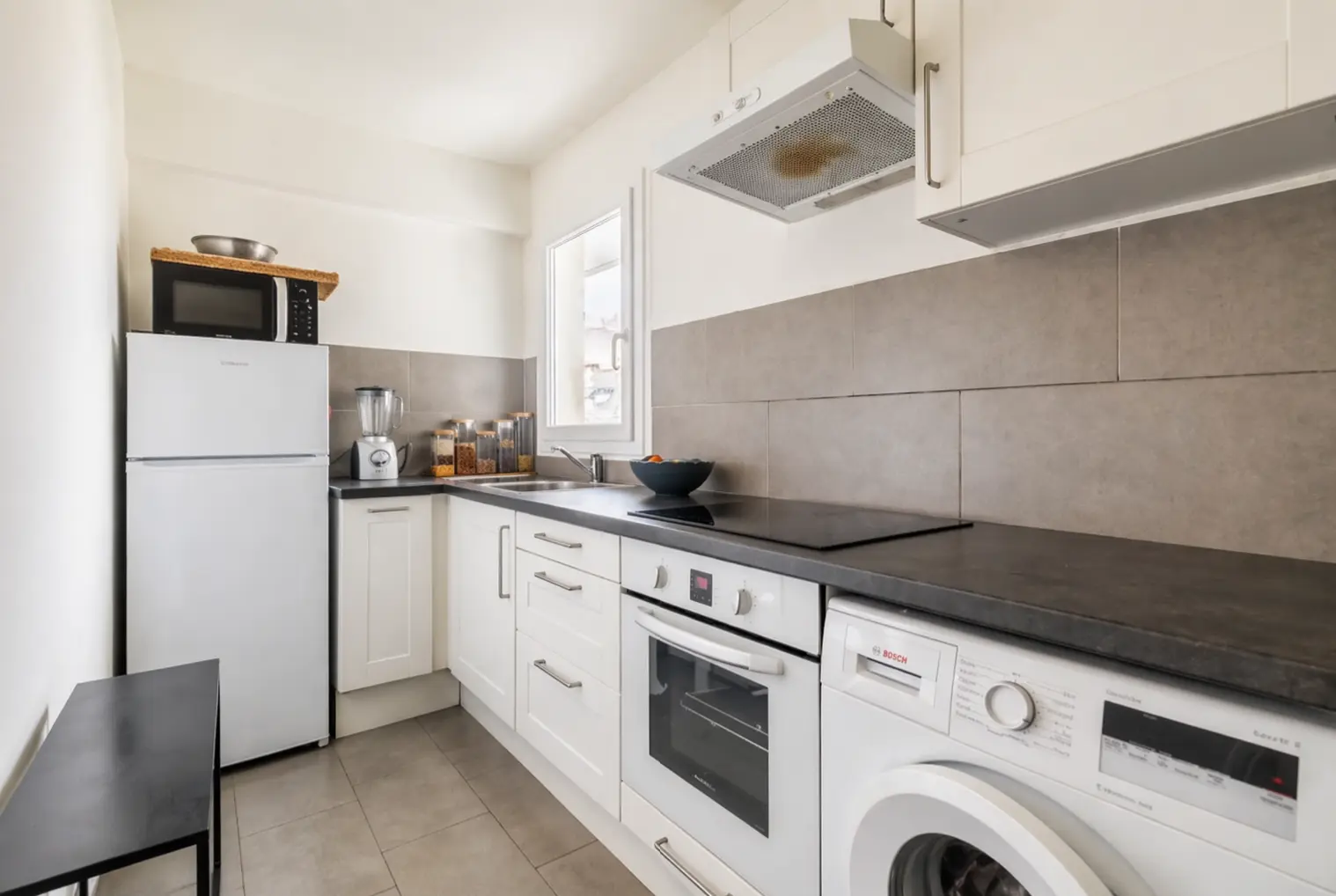 Modern white galley kitchen with grey tile backsplash and integrated appliances