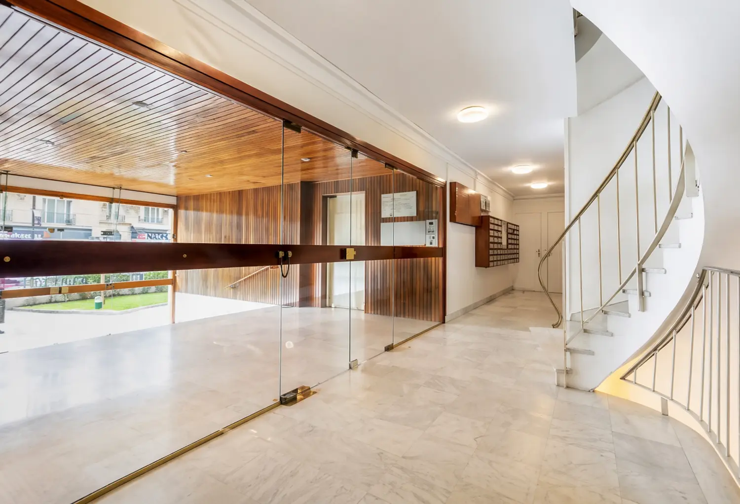 Elegant building lobby with marble floors, wooden ceiling and curved staircase