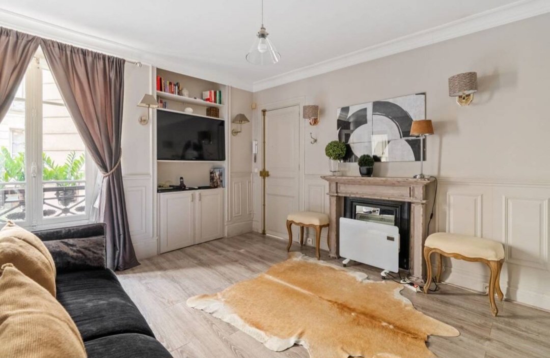 Living room with marble fireplace, mouldings and hide rug in the Rue du Bac studio — Rue du Bac · Paris 7e