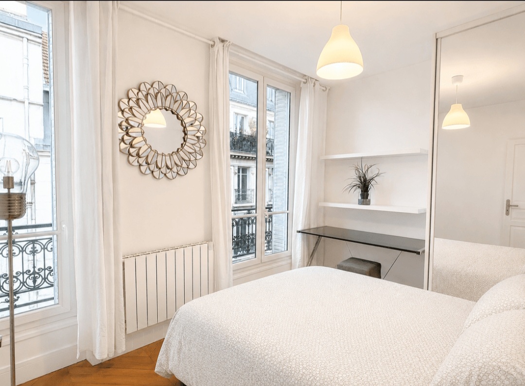Second bedroom with sunburst mirror, workspace and abundant natural light — Le Marais · Paris 4e