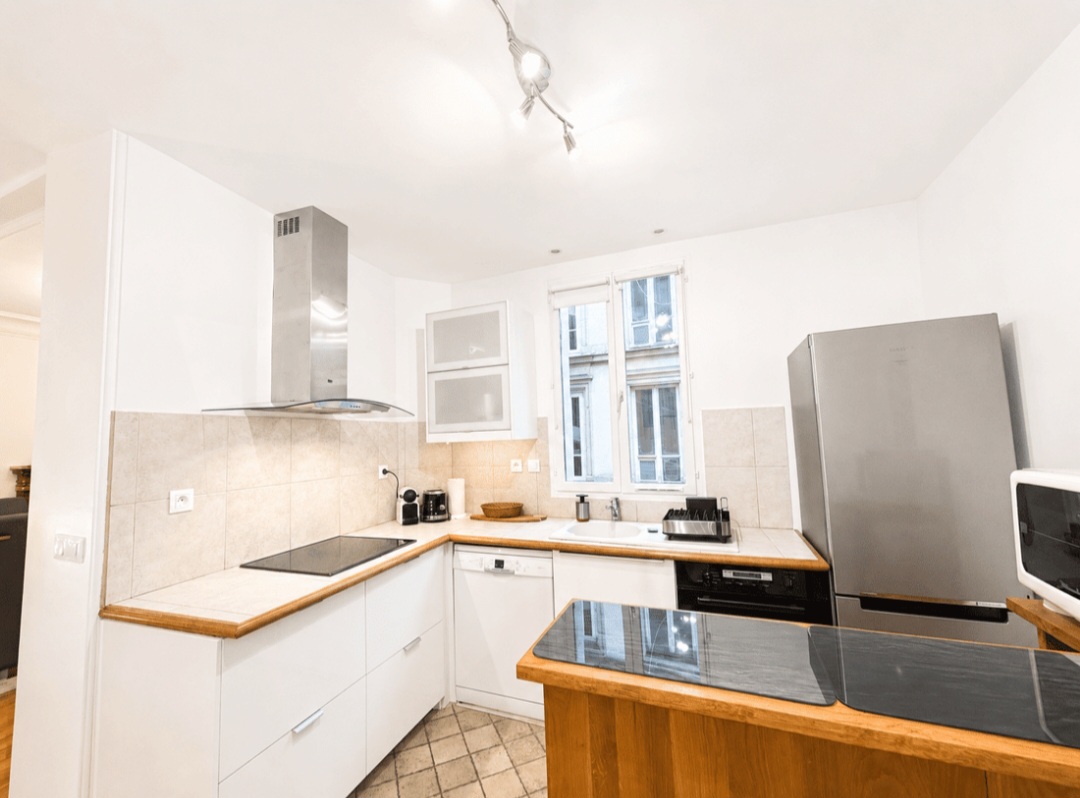 Fully equipped open-plan kitchen with oven, ceramic hob, dishwasher and large fridge-freezer — Le Marais · Paris 4e