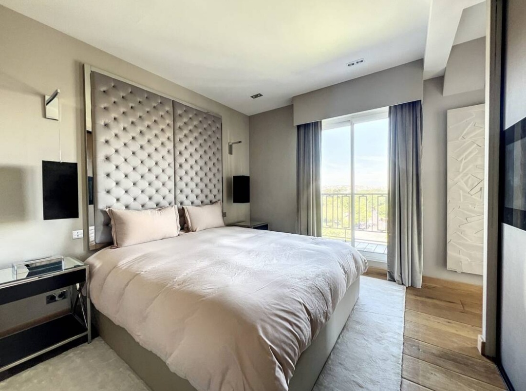 Principal bedroom with tufted headboard and balcony access