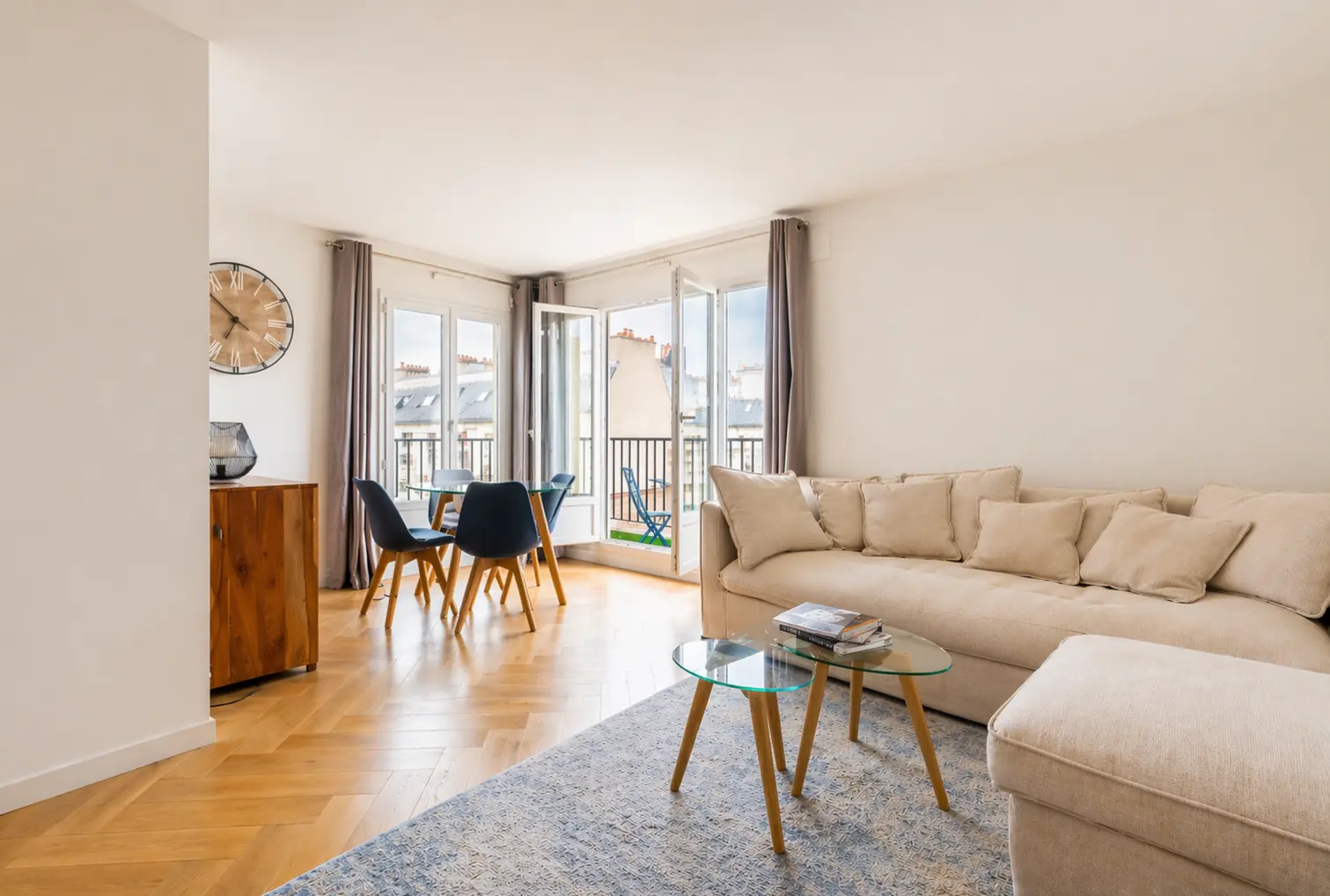 Sunlit living room with light wood floors and a large beige sectional sofa