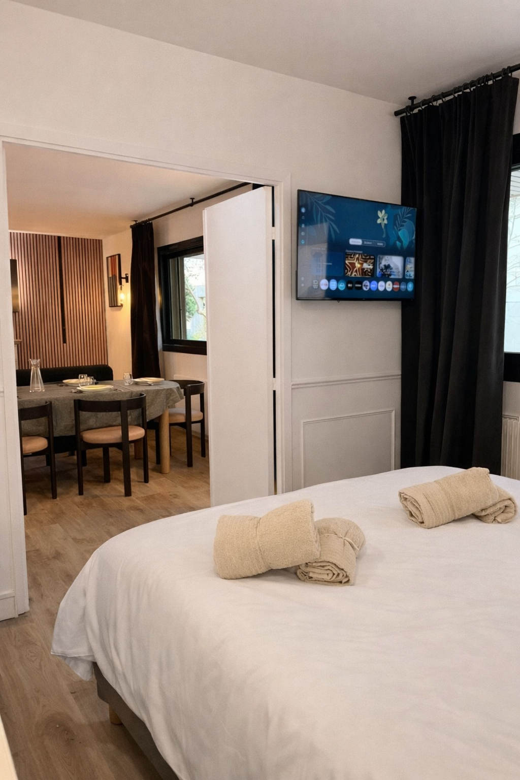 Second bedroom with double bed, wall-mounted TV and view to the dining area — Paris 16th · Auteuil, Paris, France