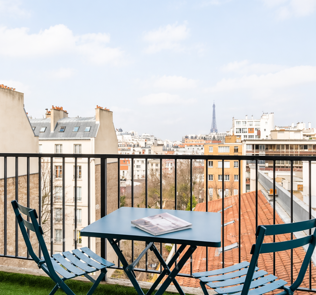 Balcony with artificial grass and a blue bistro set overlooking the Eiffel Tower