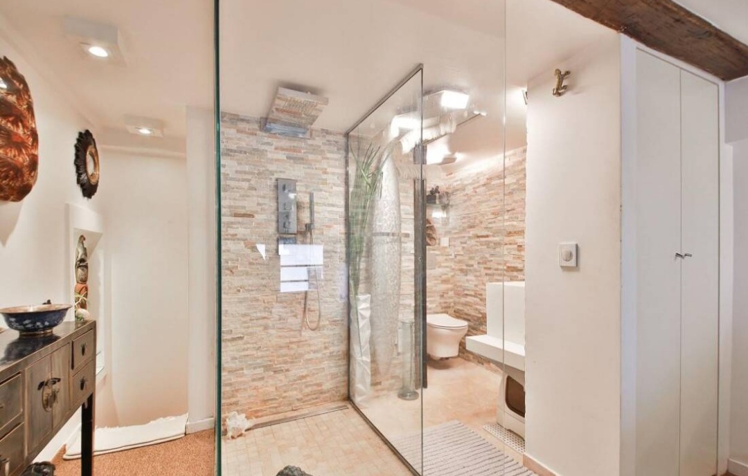 Glass walk-in shower with stone tiling in the duplex bathroom