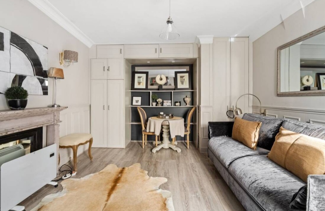 Overview of the studio living space with panelled walls, dining nook and sofa bed — Rue du Bac · Paris 7e